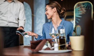 A woman at a business lunch paying with her corporate debit card